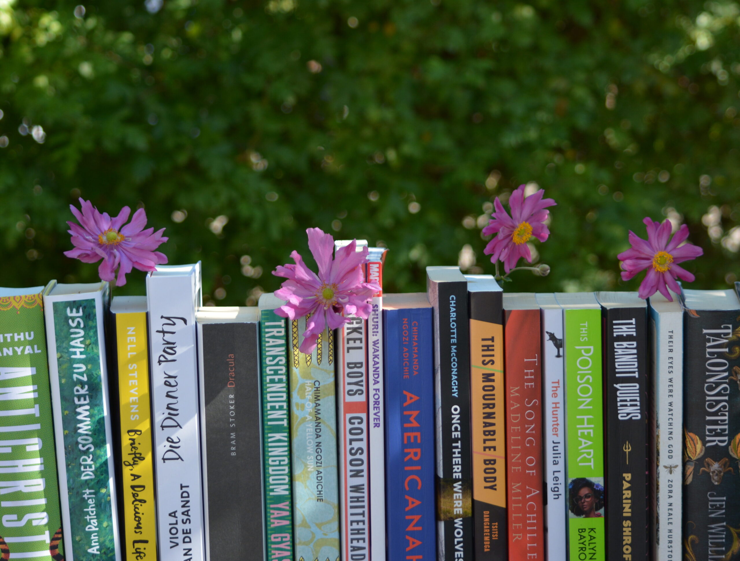 Buchrücken und lila Blüten vor grünem Hintergrund